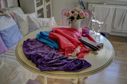 Die Grundzutaten, Stoffe in Violett, Pink und Türkis. Kristallgläser, rosafarbene Rosen, Lila Kerzen und Teelichter